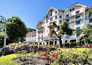 Ein mehrstöckiges Hotel mit Balkonen, einem Blumengarten und blauem Himmel.