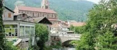 A river flowing through a town with a bridge, buildings, and a church spire.