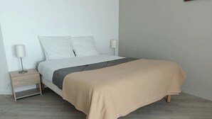 Quarto com cama, mesas de cabeceira e abajur.