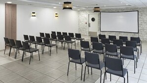 Ett konferensrum med rader av stolar, en projektorduk och en whiteboard.