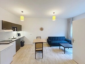 A compact living space with a kitchenette, a dining table, a sofa, and a small coffee table. - Appartement 3 étoiles - ccbgffg (Rouen)