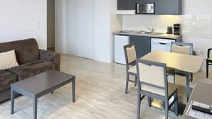 A compact living space with a kitchenette, a sofa, a dining table with chairs, and a coffee machine. - Appartement 3 étoiles - ccbgffh (Rouen)