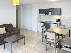 A compact living space with a kitchenette, a sofa, a dining table with chairs, and a coffee machine. - Appartement 3 étoiles - ccbgffh (Rouen)