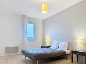 A bedroom with a bed, two bedside tables, a window, and a ceiling light. - Appartement 3 étoiles - ccbgffh (Rouen)