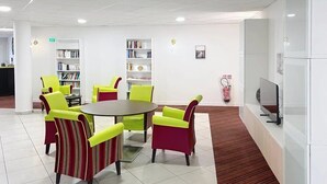 A modern waiting area with a round table, chairs, and a television. - Appartement 3 étoiles - ccbgffh (Rouen)