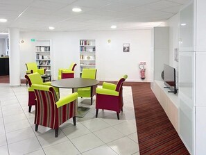 A modern waiting area with a round table, chairs, and a television. - Appartement 3 étoiles - ccbgffh (Rouen)