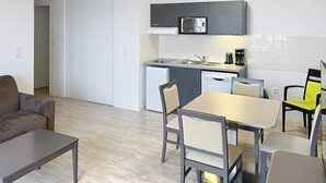 Um espaço compacto com cozinha compacta, área de refeições e sofá.