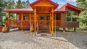Een vakantiehuis in blokhutstijl met een veranda, een terras en een apart bijgebouw.