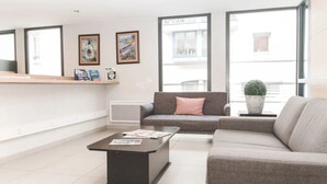 En moderne stue med en sofa, et sofabord og en potteplante.