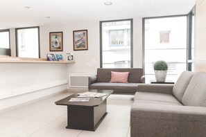 Ein modernes Wohnzimmer mit einer Couch, einem Couchtisch und einer Topfpflanze.