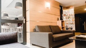 En moderne stue med en grå sofa, et sofabord og en bogreol fyldt med magasiner.