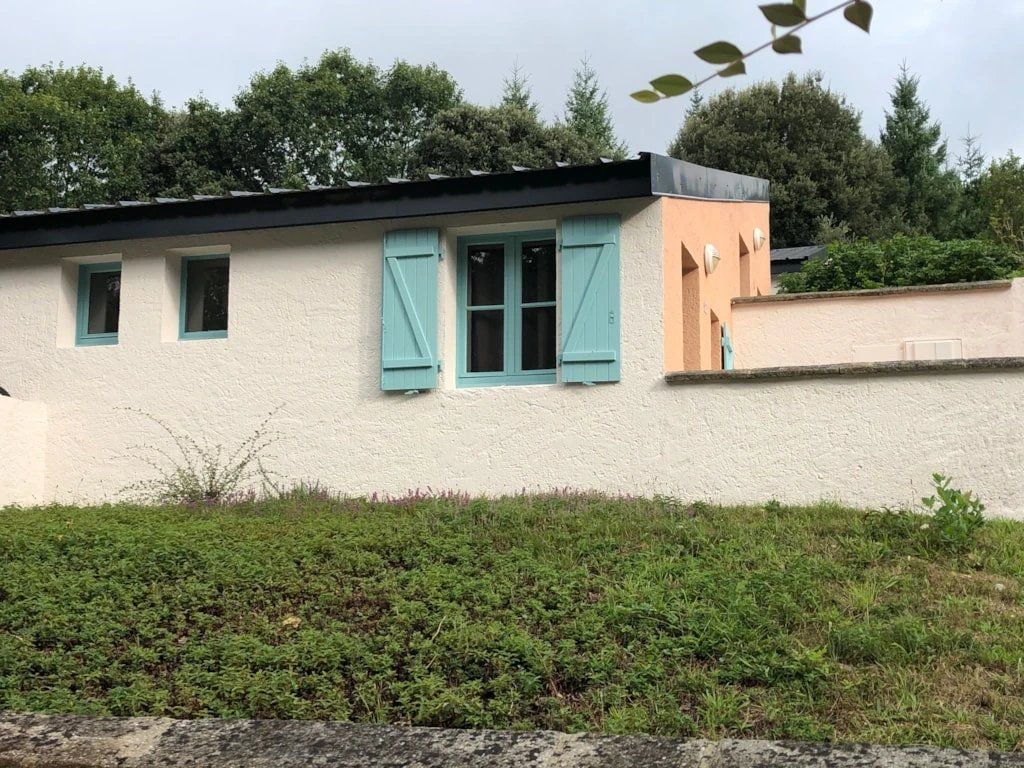 A building with a white exterior, teal shutters, and a peach-colored section.