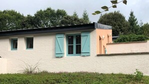 Ein Gebäude mit weißer Fassade, türkisblauen Fensterläden und einem pfirsichfarbenen Abschnitt.