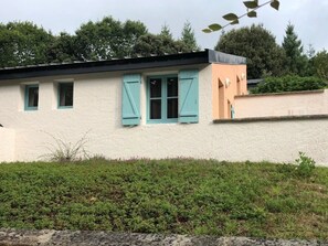 Ein Gebäude mit weißer Fassade, türkisblauen Fensterläden und einem pfirsichfarbenen Abschnitt.
