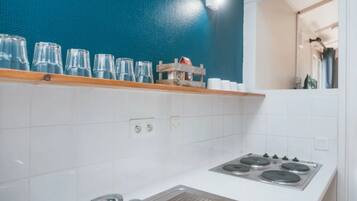 A kitchen with white tiles, a stove, and a blue wall.