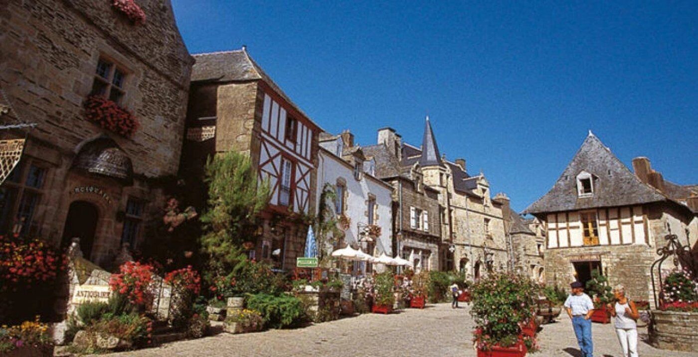 A cobblestone street lined with historic buildings, some with visible signage.