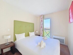 Une chambre d’hôtel avec un lit, une table de chevet, une lampe et une fenêtre donnant sur un paysage agréable.