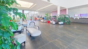 Eine geräumige Lobby mit Sitzbereichen, Topfpflanzen und einem Empfangstresen.