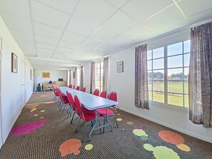 A conference room with a long table and red chairs, large windows, and a carpet with colorful patterns. - Appartement 3 étoiles - Piscine  - ccbgeeh (Amboise)