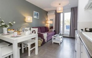 Et moderne hotelværelse med spiseplads, sofa og tekøkken.