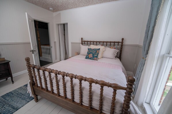 A bedroom with a wooden bed, a door leading to a balcony, and a small bedside table.