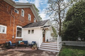 A brick house with a white exterior, a porch with steps, and outdoor seating.