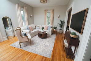 Un salon comprenant un canapé, un fauteuil, une table basse et un grand miroir.