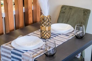 Een eettafel met witte borden, een glas en een decoratieve vaas met een veer.