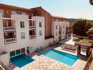 A residential building with a swimming pool, balconies, and a view of the surrounding area.
