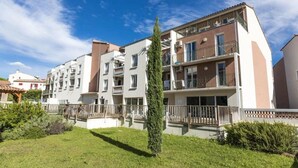 Ein Mehrfamilienhaus mit mehreren Etagen, Balkonen und einem gepflegten Rasen.