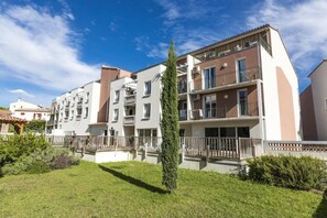 A residential building with multiple floors, balconies, and a well-maintained lawn. - Appartement 3 étoiles - Piscine  - ccbgfcd (Gréoux-les-Bains)