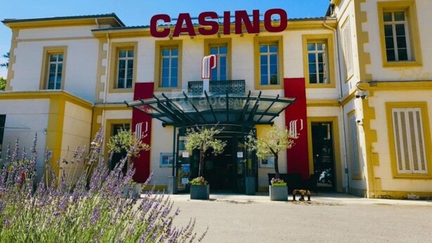 Ein Gebäude mit einem auffälligen 'CASINO'-Schild, einem überdachten Eingang und einer symmetrischen Fassade mit gelben und roten Akzenten.