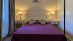 Ein Hotelzimmer mit einem Bett, zwei Nachttischen und einem Fenster mit Vorhängen.