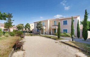Un immeuble résidentiel avec une allée pavée, un banc et une pelouse bien entretenue.