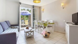 A room with a sofa, dining table, chairs, a television, and a balcony with a view. - Appartement 3 étoiles - ccbgfbg (Cabriès)