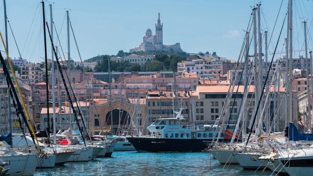 A marina with multiple boats docked, a prominent building with a dome and tower in the background, and a densely built urban area with various buildings. - Appartement 3 étoiles - ccbgfbg (Cabriès)