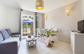 Une pièce comprenant un canapé, une table à manger, des chaises, un téléviseur et un balcon avec vue.