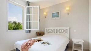 A bedroom with a bed, a nightstand, a window with curtains, and wall-mounted lights. - Camping 3 étoiles - ccbgfbi (Cabriès)