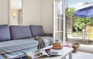 Ein Zimmer mit einer Couch, einem Tisch mit einer Zeitschrift und Blick ins Freie.