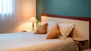 Een opgemaakt bed met kussens, een bedlampje en een houten hoofdbord in een hotelkamer.