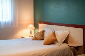 A neatly made bed with pillows, a bedside lamp, and a wooden headboard in a hotel room. - Appartement 2 étoiles - ccbgff0 (Brest)