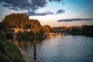 A riverside view with a bridge, trees, and buildings in the background. - Camping 3 étoiles - ccbg00e (Neuilly-sur-Marne)
