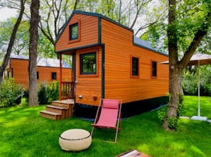 A small wooden cabin with a porch, steps, and a red chair. - Camping 3 étoiles - ccbg00e (Neuilly-sur-Marne)