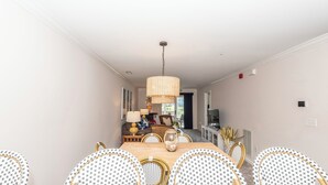 A dining area with a wooden table, wicker chairs, and a hanging light fixture. - Rehoboth Perfect 2BR Condo sleeps 6 with a Pool (Rehoboth Beach)