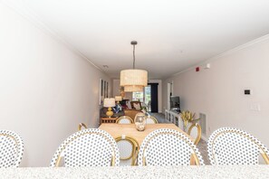 Un comedor con mesa de madera, sillas de mimbre y una lámpara colgante.