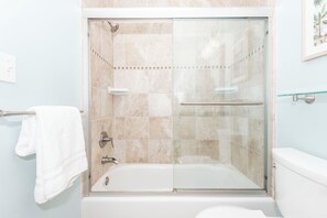 Un baño moderno con ducha envuelta en vidrio, una bañera blanca y un inodoro.