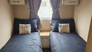 Una habitación pequeña y acogedora con dos camas, cada una con almohada y cabecero.