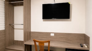 A compact room with a built-in desk, a television mounted on the wall, a small refrigerator, and a wooden chair. - Barrio Inn Morelos (Monterrey)