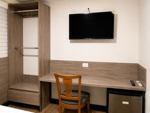 A compact room with a built-in desk, a television mounted on the wall, a small refrigerator, and a wooden chair. - Barrio Inn Morelos (Monterrey)