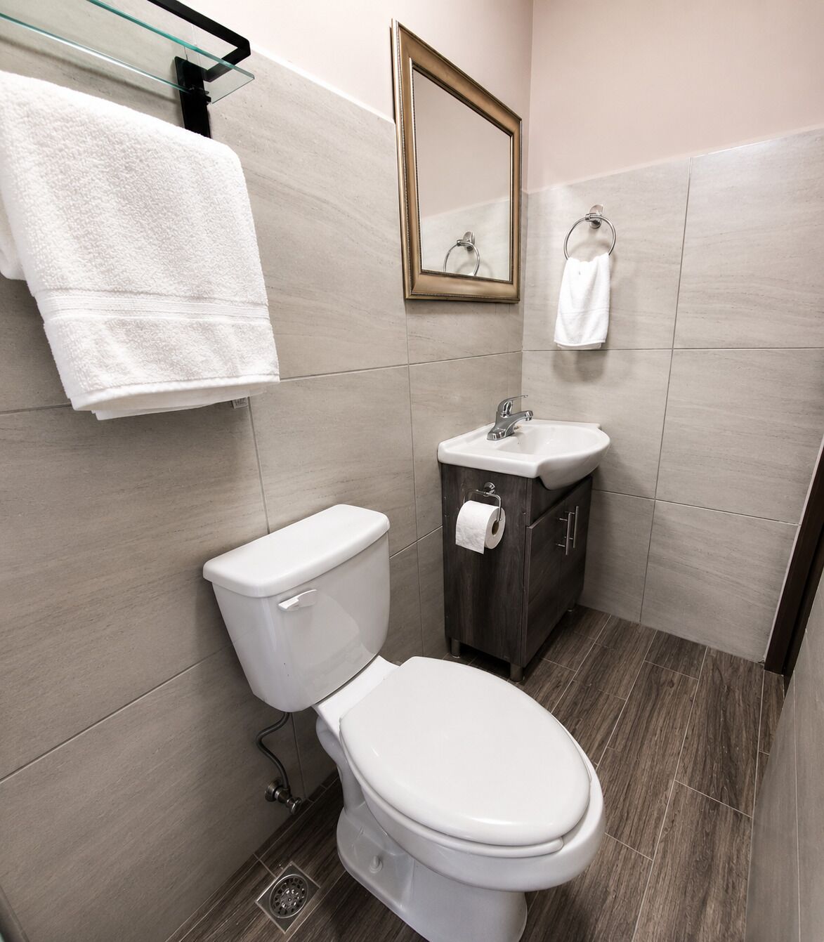 Egy modern fürőszoba, amelyben WC, mosdókagyló és tükör található.